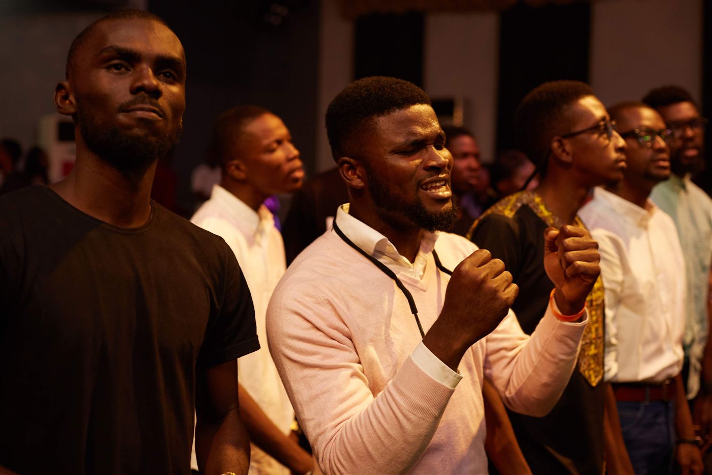 Young men standing side by side, singing in worship