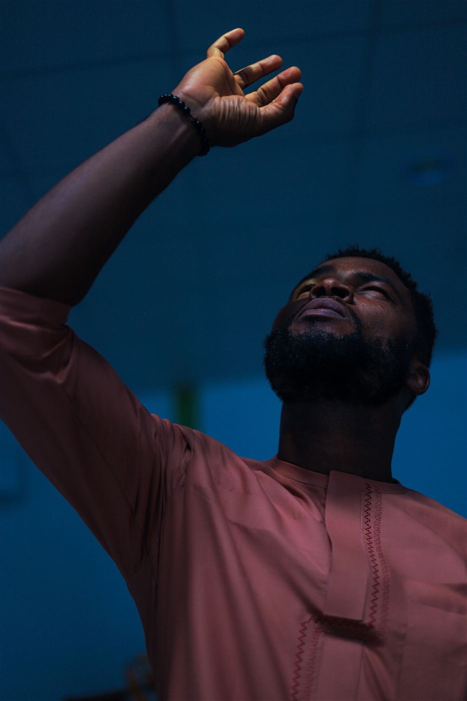A man in worship, face lifted and hand raised toward the light